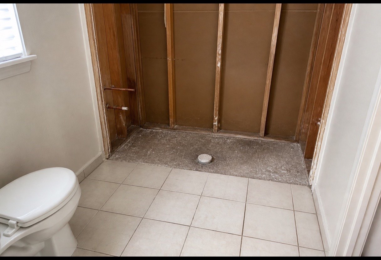 The alcove with the old tub gone. This is the only moment the wall behind it is visible and cheap to put right